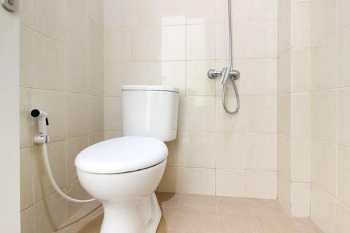 La salle de bains est pourvue d'une douche et de toilettes blanches. dans l'établissement RedDoorz near Jogja City Mall 3, à Sleman