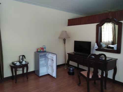 a room with a piano and a desk with a mirror at Crown Royale Hotel in Balanga