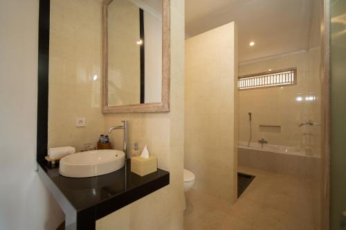 uma casa de banho com um lavatório, um WC e um espelho. em Puri Sedana Ubud Villa em Ubud