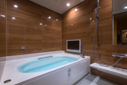 a bathroom with a tub with a tv on the wall at HOTEL FARINA DOLCE (Adult Only) in Kanuma