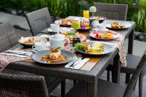 a wooden table with plates of food on it at Sense Canggu Beach Hotel in Canggu