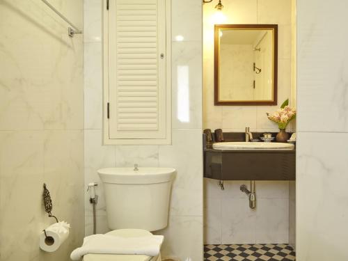 a bathroom with a toilet and a sink and a mirror at SSIP Boutique Dhevej Bangkok in Bangkok