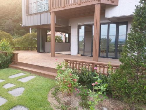 a house with a wooden deck and some flowers at Grace River House Block A - Couple Room in Hoengseong