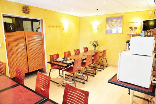 a dining room with a table and chairs and a refrigerator at Hotel De Rosny in Tours