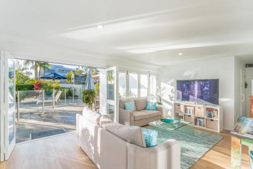 a living room with a couch and a tv at Noosa Boutique Apartments & Elkhorn Villas in Noosa Heads