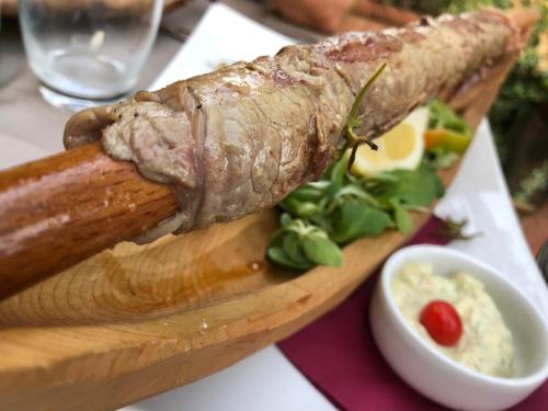 a piece of meat on a cutting board next to a bowl of sauce at Hotel Concordia in Porlezza