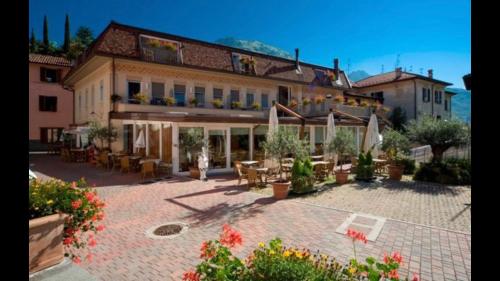 a large building with a patio in front of it at Hotel Concordia in Porlezza