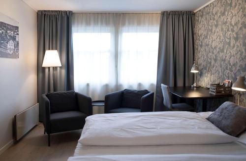 a bedroom with a bed and two chairs and a table at Best Western Tingvold Park Hotel in Steinkjer