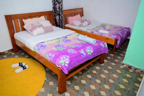 two twin beds in a room with a rug at Kenya Inn in Nairobi