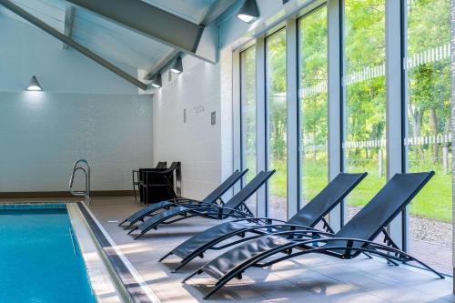 a pool with chairs next to a swimming pool at Holiday Inn Newcastle South by IHG in Boldon