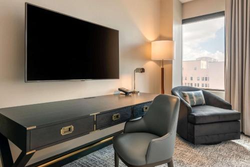 a hotel room with a tv and a chair and a desk at Cambria Hotel Houston Downtown Convention Center in Houston