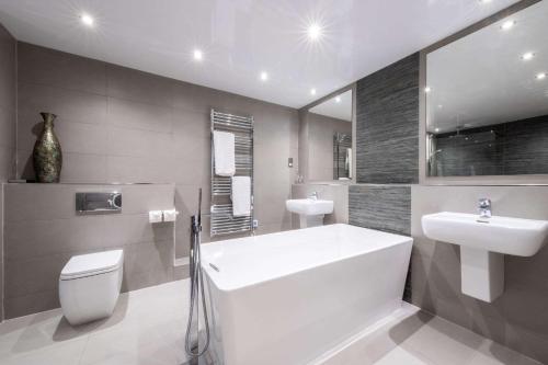 a bathroom with a tub and a toilet and a sink at Clarion Hotel Newcastle South in Sunderland