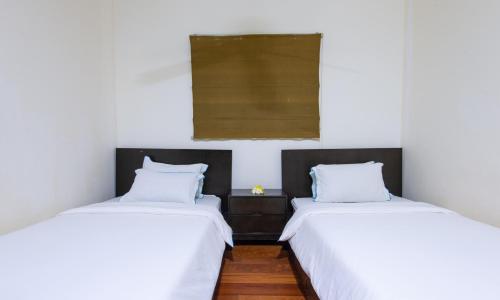 two beds in a room with white sheets and blue pillows at Sabah Beach Villas & Suites in Kota Kinabalu