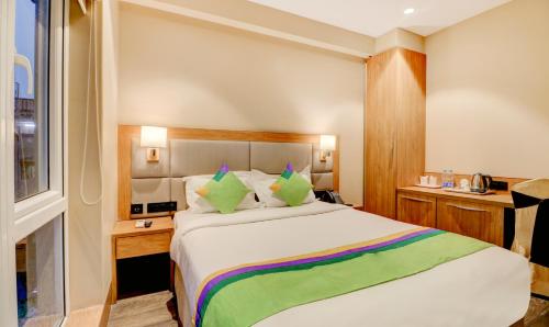a bedroom with a large white bed with green pillows at Treebo Radhe Palace, Lake Town in Kolkata