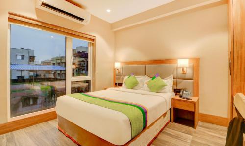 a bedroom with a bed and a large window at Treebo Radhe Palace, Lake Town in Kolkata