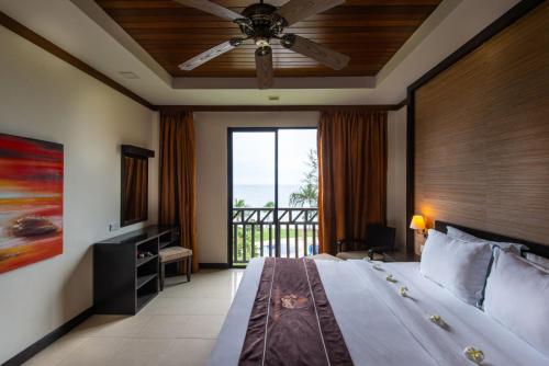 a bedroom with a large bed and a balcony at Sabah Beach Villas & Suites in Kota Kinabalu