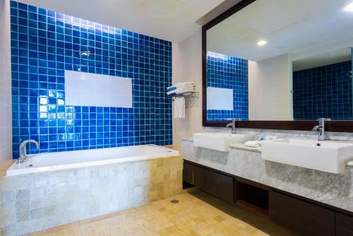 a bathroom with two sinks and a tub and a mirror at Sabah Beach Villas & Suites in Kota Kinabalu