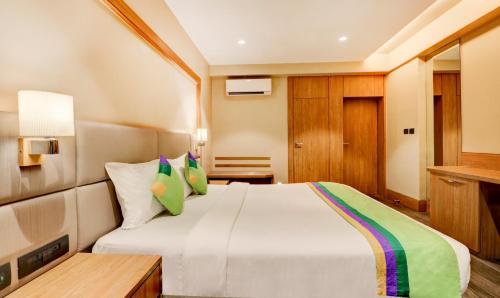 a bedroom with a large white bed with green pillows at Treebo Radhe Palace, Lake Town in Kolkata