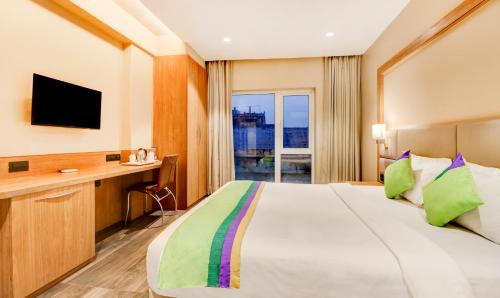 a bedroom with a bed and a desk with a television at Treebo Radhe Palace, Lake Town in Kolkata