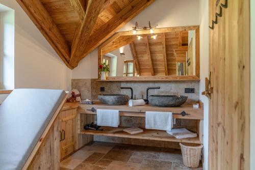a bathroom with two sinks and a wooden ceiling at Almchalet Linharterhof in Haus im Ennstal