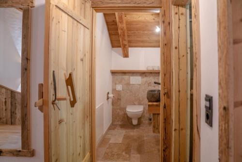 a bathroom with a toilet and a wooden door at Almchalet Linharterhof in Haus im Ennstal