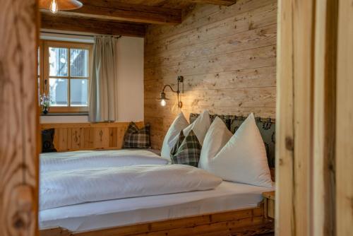 a bed in a room with a wooden wall at Almchalet Linharterhof in Haus im Ennstal