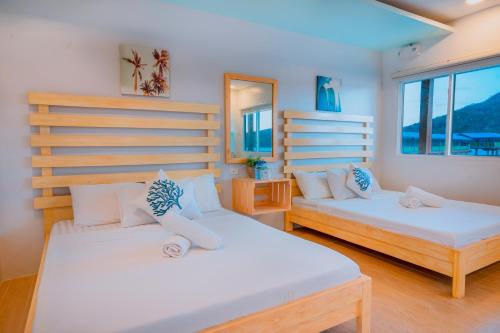 two beds in a room with two windows at Coron Underwater Garden Resort in Coron