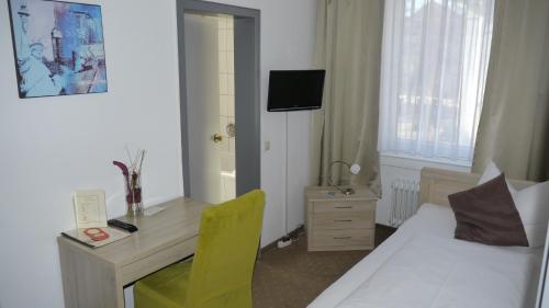 a hotel room with a bed and a desk with a yellow chair at Parkhotel Villingen und Boardingzimmer in Villingen-Schwenningen