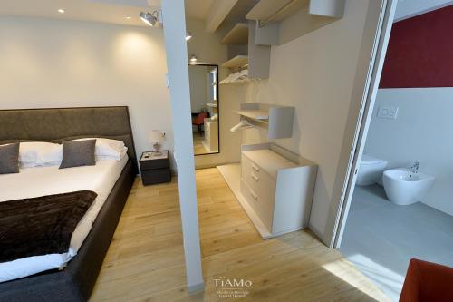 a bedroom with a bed and a bathroom with a mirror at TiAMo Modern Design Guest House in Ronchi dei Legionari