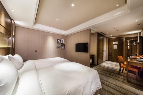 a bedroom with a large white bed and a desk at Green World Taipei Station in Taipei