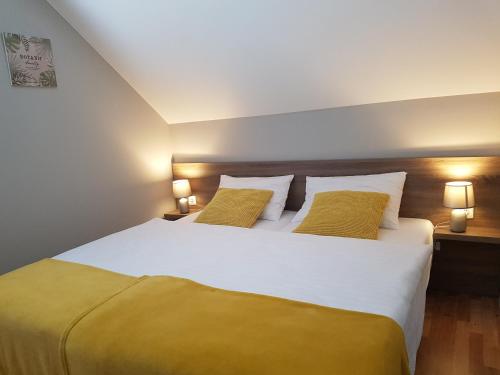 sypialnia z dużym białym łóżkiem z 2 żółtymi poduszkami w obiekcie Corden Village w Łebie