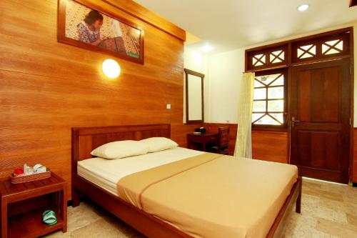 a bedroom with a bed and a wooden wall at The Soemarsono Hotel in Yogyakarta