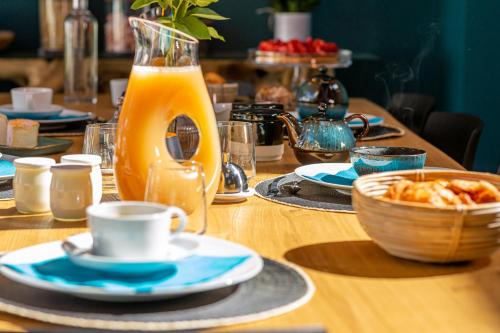 Ein Holztisch, gedeckt mit Tellern voller Essen und einem Krug Orangensaft in der Unterkunft La Ressourçante in Puisieulx