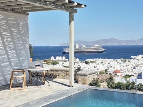 a patio with a table and a view of the city at Belvedere Mykonos - Hilltop Rooms & Suites - The Leading Hotels of the World in Mýkonos City