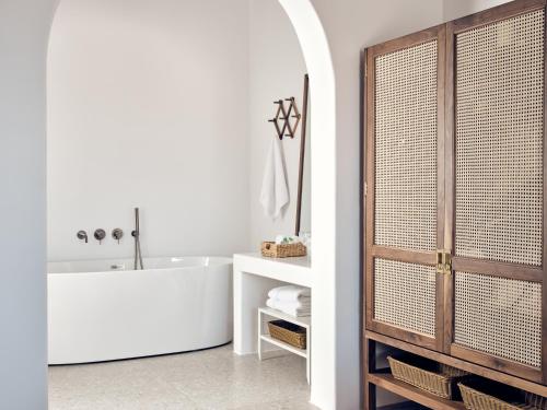 a bathroom with a white tub and a sink at Belvedere Mykonos - Hilltop Rooms & Suites - The Leading Hotels of the World in Mýkonos City