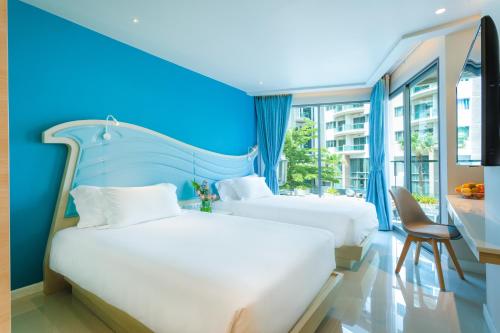 Centara Sonrisa Residences & Suites Sriracha في سي راشا: سريرين في غرفة ذات جدار أزرق