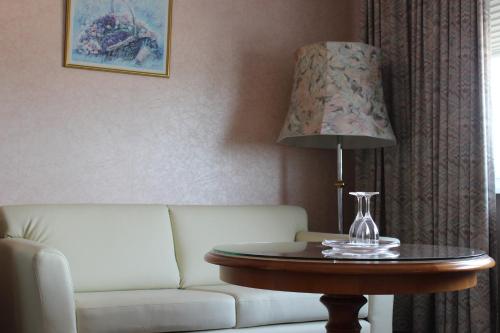 ein Wohnzimmer mit einem Sofa und einem Tisch mit einer Lampe in der Unterkunft Wiking Hotel in Henstedt-Ulzburg