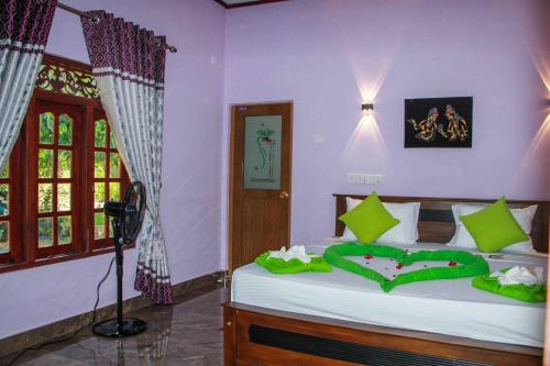Un dormitorio con una cama con sábanas verdes y una cámara. en Wijesiri Family Guest House, en Sigiriya