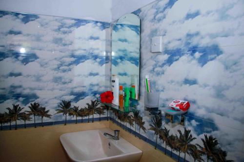 a bathroom with a mural of clouds and palm trees on the wall at Wijesiri Family Guest House in Sigiriya