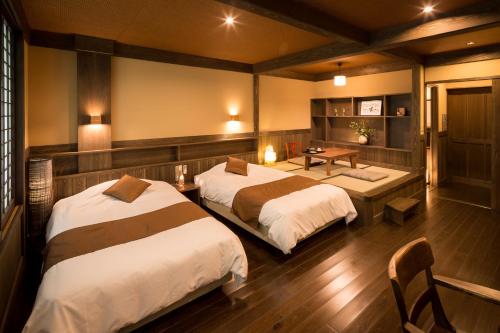 a bedroom with two beds and a table and a desk at Ryokan Wakaba in Minamioguni