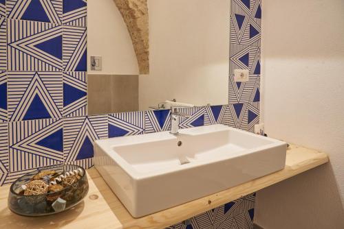 a white sink in a bathroom with blue and white tiles at Style Home in Salerno