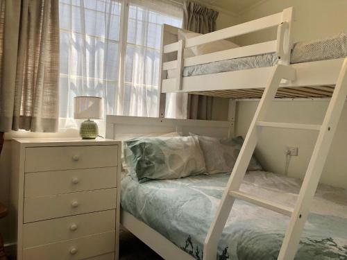 a bedroom with a bunk bed and a dresser at Recreation Cottage in Kingston Beach