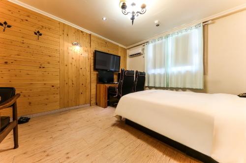 a bedroom with a white bed and a flat screen tv at Manhatan Hotel 청주 in Cheongju