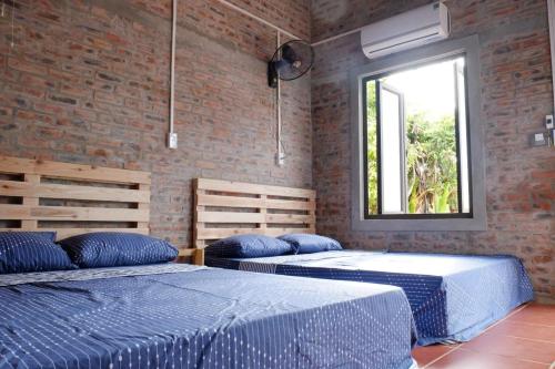 two beds in a room with a window at Datani Mộc Châu Homestay in Làng Môn