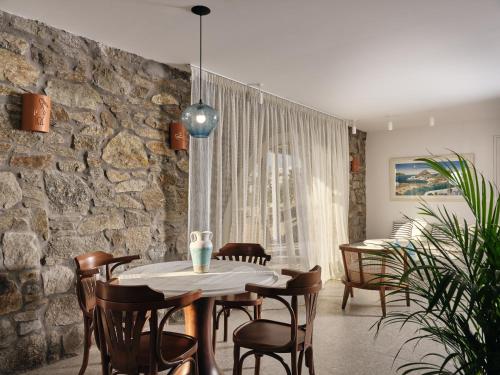 a dining room with a stone wall and a table and chairs at Belvedere Mykonos - Hilltop Rooms & Suites - The Leading Hotels of the World in Mýkonos City