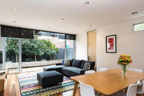 a living room with a blue couch and a table at Bradman Modern Style a Walk to MCG, Swan St, CBD in Melbourne