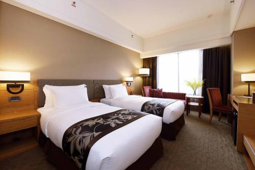 a hotel room with two beds and a desk at Fullon Hotel Hualien in Hualien City