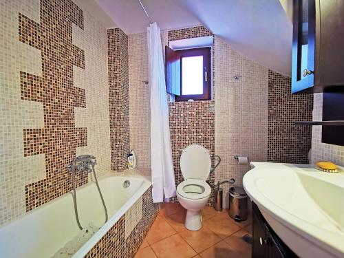 a bathroom with a toilet and a tub and a sink at Anaroussa Diros Maisonette in Areopoli