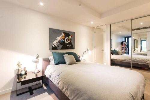 a bedroom with a large bed and a mirror at Laurent Balcony Views Steps from Laneway Vibes in Melbourne