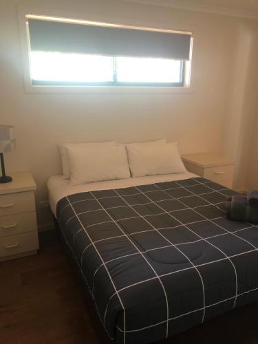 a bedroom with a bed and a window at Latitude20 Karratha Apartments in Karratha